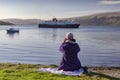 Ferry leaving craignure port in mull with woman photographing the scene