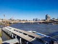 Ferry pier at river thames in London sunny blue winter day sunshine sky no clouds view bridges London city skyscraper uk