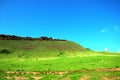 Fertile pasture on the slope of a high hill with the remains of ancient buildings at the top