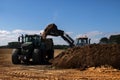 Fertilize the field, excavator with shovel fills manure in the t