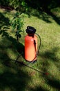 Fertilizer sprayer orange bottle on lawn. Seasonal garden work concept