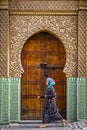 Fes, Morocco - Circa September 2015 - a traditionally dressed lady in front of an old medina building Royalty Free Stock Photo