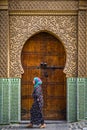 Fes, Morocco - Circa September 2015 - a traditionally dressed lady in front of an old medina building Royalty Free Stock Photo