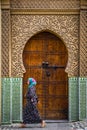 Fes, Morocco - Circa September 2015 - a traditionally dressed lady in front of an old medina building Royalty Free Stock Photo