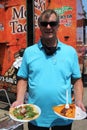 Man holds plates of tacos and tamales at Latino street fair food festival in Chicago Illinois USA
