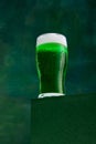 Festival drink. Glass of foamy frothy green beer over dark green background. Traditional hop taste. Concept of st Royalty Free Stock Photo