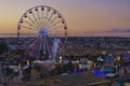 Festival Ferris wheel against sunset pink sky and urban scenery of Malta. Christmas market in La Valette during