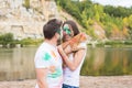 Festival holi, holidays, tourism and nature concept - Couple dressed in white shirts holding cat and covered with Royalty Free Stock Photo