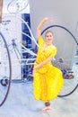 the festival of plasticine rain. A girl in beautiful Indian attire is dancing. Behind her stands a large bicycle construction