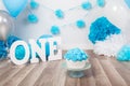 Festive background decoration for birthday celebration with gourmet cake, letters saying one and blue balloons in studio Royalty Free Stock Photo