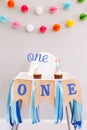 Festive background decoration for birthday celebration. Letters text one and one candle in small cupcakes for a baby child