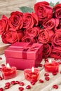 Festive background to the Valentine`s day. A bouquet of red roses, a gift box and a heart-shaped candle. Royalty Free Stock Photo