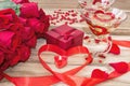 Festive background to the Valentine`s day. A bouquet of red roses, a gift box, a heart-shaped candle and a red ribbon with a heart Royalty Free Stock Photo