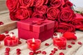 Festive background to the Valentine`s day. A bouquet of red roses, a gift box and a heart-shaped candle. On a wooden background. Royalty Free Stock Photo