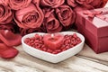 Festive background to the Valentine`s day. A bouquet of red roses, a gift box, a heart-shaped plate and a heart-shaped candle. Royalty Free Stock Photo