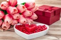 Festive background to the Valentine`s day. A bouquet of tulips, a gift box, a heart-shaped plate and a heart-shaped candle. Royalty Free Stock Photo