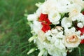 Festive beautiful bouquet of red and white flowers on green grass with wedding rings