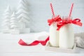 Festive bottles of milk with bows and straws on white wooden background with Christmas trees decorations Royalty Free Stock Photo