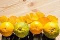 Juicy yellow and green tangerines and leaves of ginkgo tree on a fresh raw wooden table.