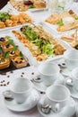 Festive buffet. An assortment of cold snacks on wooden crossbars and pancakes decorated with leaves of greens, jam and Royalty Free Stock Photo