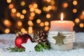 Festive Christmas holiday celebration candle on snow with xmas ornaments decoration and lights background Royalty Free Stock Photo