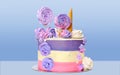 Festive cake with colored stripes of pink and purple decorated with multicolored marshmallows on a blue background for decoration