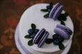 A festive cake in lilac style decorated with cakes, macaroni cookies with filling, fruits and berries on the cake