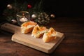 Festive canapes, baguette bread with cheese cream and salmon on a wooden kitchen board, dark rustic table with Christmas