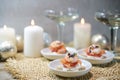 Festive canapes with shrimps and salmon, champagne drink glasses and candles, appetizer snack for a holiday party on Christmas or Royalty Free Stock Photo