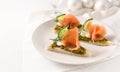 Festive canapes with smoked salmon on a plate on a white table with christmas decoration, large copy space