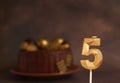 Festive candle number 5 on the background of a chocolate cake on a dark background Royalty Free Stock Photo