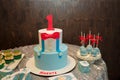 Festive candy bar for one year old boy birthday party. Cake with red number 1 and butterfly bow on shirt. Blue cakepops