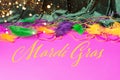 Festive carnival background. Green curtain multicolored feather beads necklace for festival magenta background Royalty Free Stock Photo