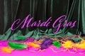 Festive carnival background text Mardi Gras, green velvet curtain colorful feather beads necklace Royalty Free Stock Photo