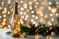 Festive champagne bottle with golden lights and Christmas decorations on bokeh background Royalty Free Stock Photo