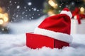 Festive Charm: Santa Claus Hat Adorning a Red Gift Box in the Snow.