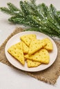 Festive cheese crackers, New Year snack concept. Cookies, fir tree branch, artificial snow, sackcloth napkin. Stone concrete Royalty Free Stock Photo