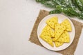 Festive cheese crackers, New Year snack concept. Cookies, fir tree branch, artificial snow, sackcloth napkin. Stone concrete Royalty Free Stock Photo