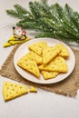 Festive cheese crackers, New Year snack concept. Cookies, mouse figure, fir tree branch, artificial snow, sackcloth napkin. Stone Royalty Free Stock Photo