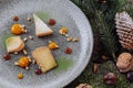 Festive Cheese Delight: Gray Plate with Pine Branches, Cones, and Nuts