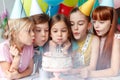 Festive children in party caps, blow candles on delicious cake, make wish, celebrate birthday, have party together, hold Royalty Free Stock Photo