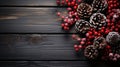 Festive Christmas arrangement with frosted pine cones and bright red berries on a textured dark wooden background, conveying a Royalty Free Stock Photo