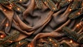 Festive Christmas Background with Pine Branches and Warm Lights on Elegant Brown Fabric