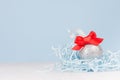 Festive christmas background - silver shiny ball with red ribbon on white wood table and pastel blue wall. Royalty Free Stock Photo