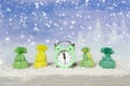 Festive Christmas banner. An alarm clock and winter woolen caps stand in the snow on a blurred blue background with snowflakes