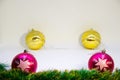 Two purple Christmas balls and two golden balls behind them and Christmas accessorieson a white background