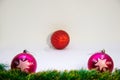 Two pink festive balls with a red ball in the middle and Christmas decoration on a white background