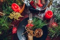 Festive Christmas dinner table setting for two decorated with fir branches, red candles, cones, ornaments. Royalty Free Stock Photo