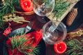 Festive Christmas dinner table setting for two decorated with fir branches, red candles, cones, ornaments. Royalty Free Stock Photo