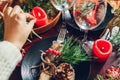 Festive Christmas dinner table setting for two decorated with fir branches, red candles, cones, ornaments. Royalty Free Stock Photo